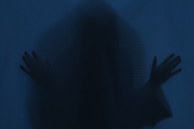 Photo of Silhouette of creepy ghost behind dark blue cloth