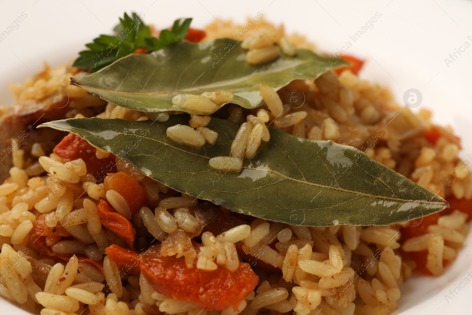 Photo of Delicious pilaf and bay leaves on plate, closeup