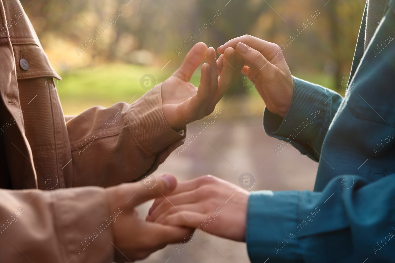 Photo of Happy young couple holding hands together outdoors, closeup. Dating agency