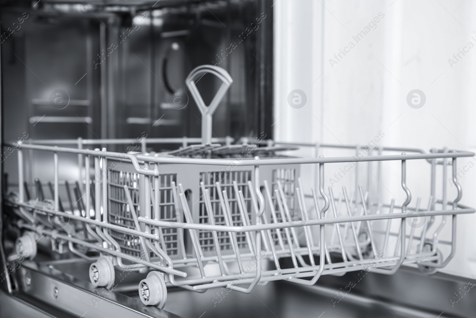 Photo of Open clean empty dishwasher in kitchen, closeup