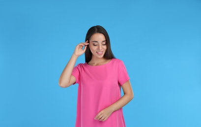 Photo of Young woman wearing pink dress on light blue background