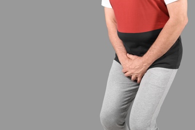 Photo of Mature man with urological problems suffering from pain on grey background