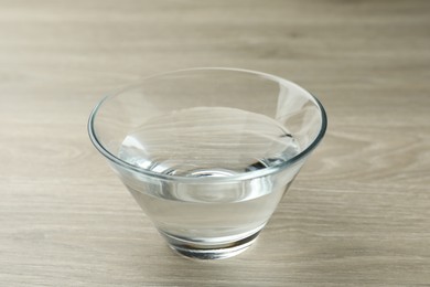Glass bowl with water on wooden table, closeup