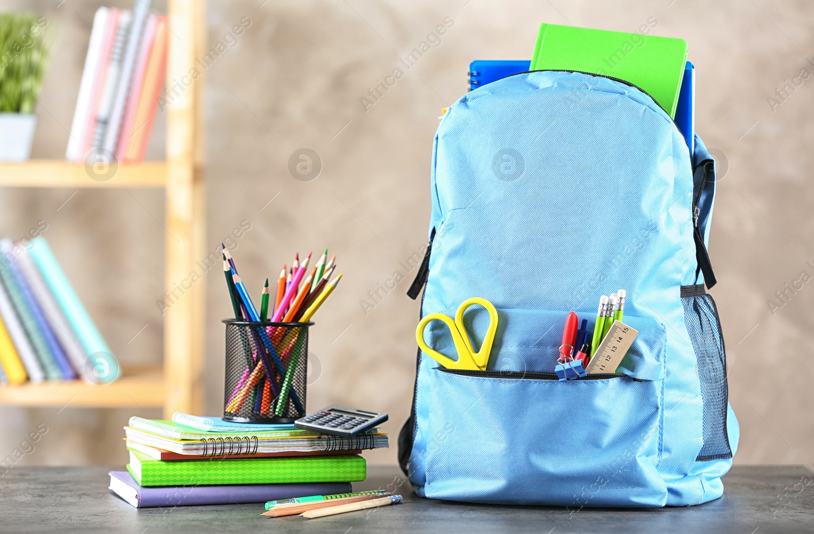 Photo of Backpack with school stationery on table indoors