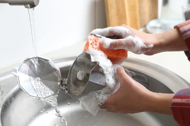 Photo of Woman washing moka pot (coffee maker) above sink in kitchen, closeup