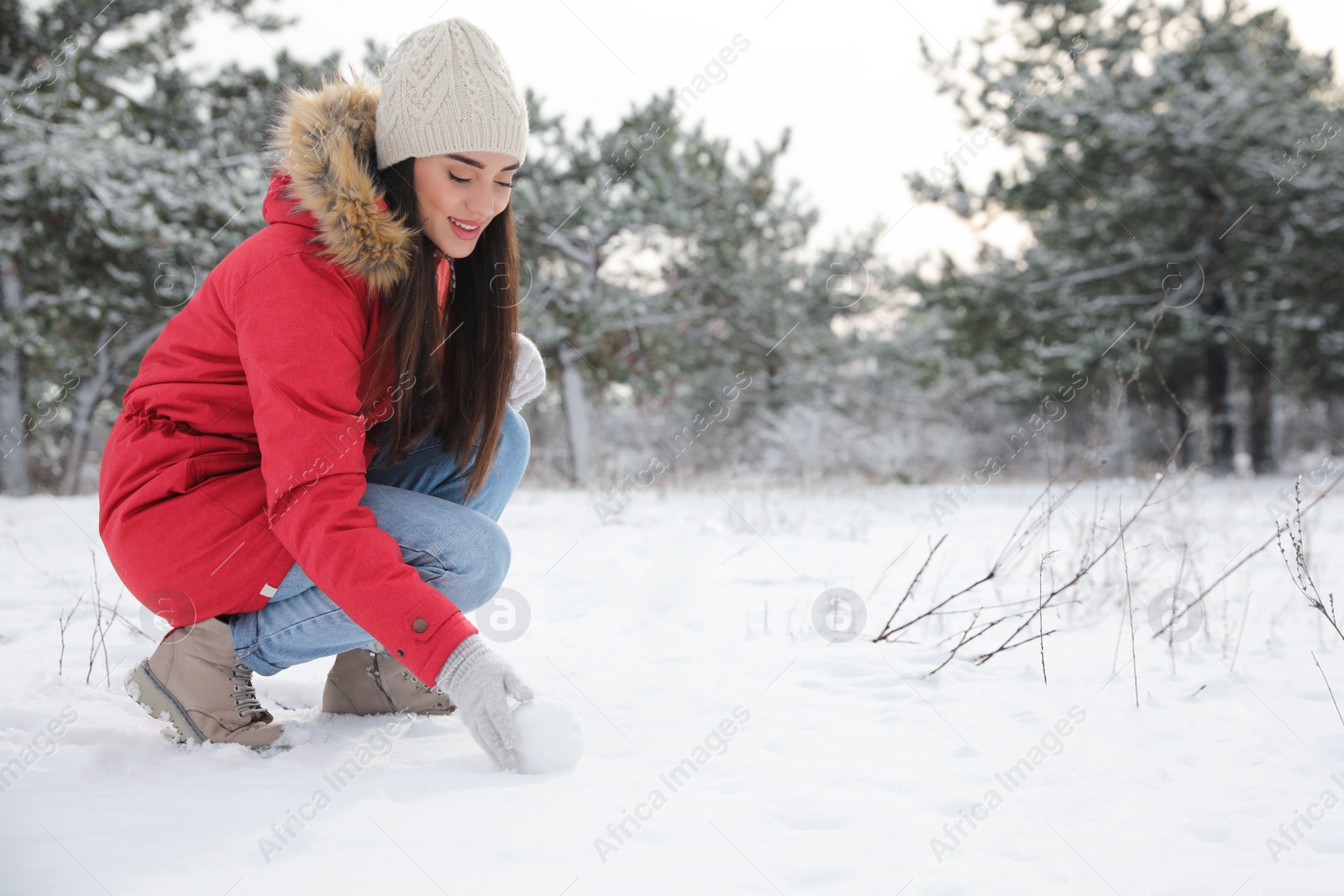 Photo of Young woman rolling snowball outdoors on winter day. Space for text