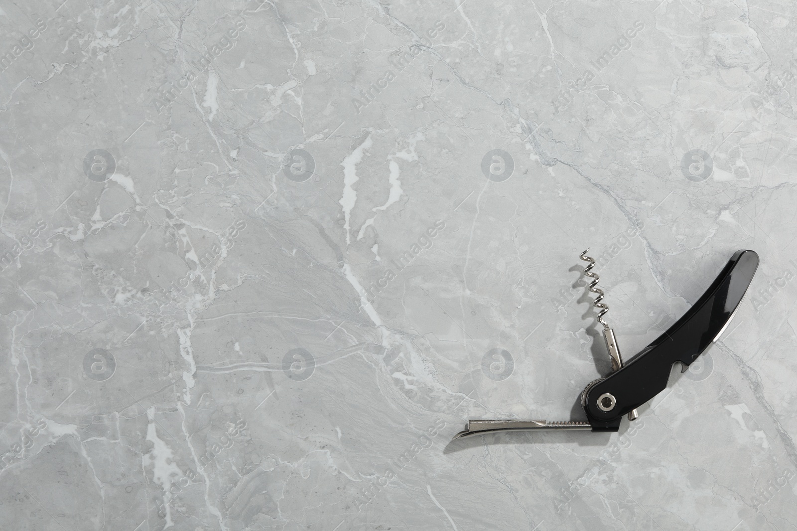 Photo of One corkscrew (sommelier knife) on grey marble table, top view. Space for text