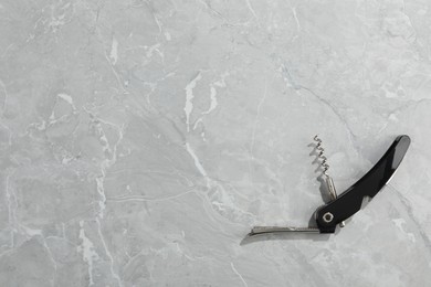 One corkscrew (sommelier knife) on grey marble table, top view. Space for text