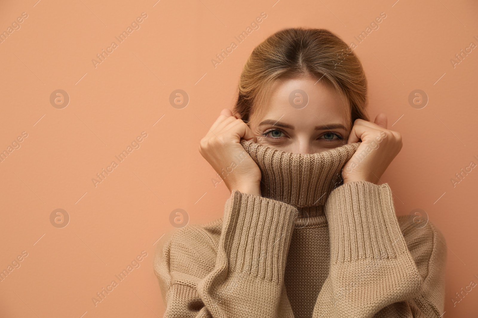 Photo of Beautiful young woman wearing knitted sweater on light brown background. Space for text