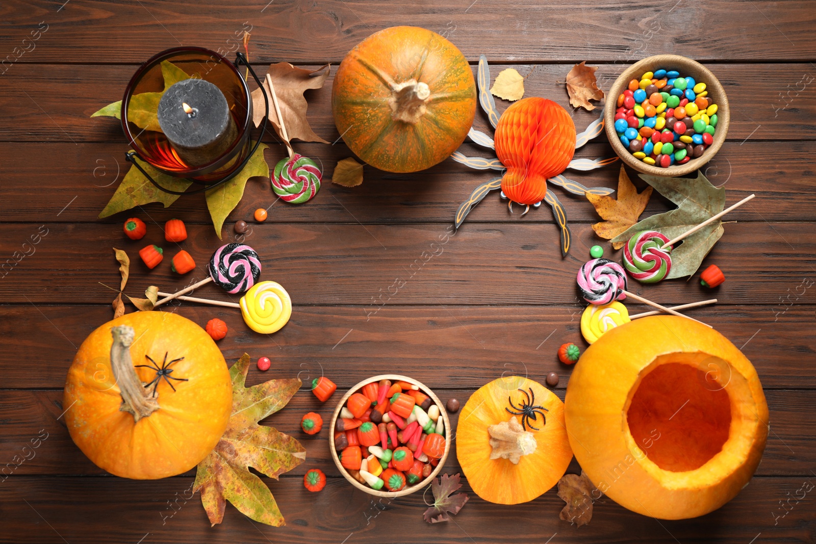 Photo of Flat lay composition with pumpkin head Jack lantern and Halloween treats on wooden background. Space for text