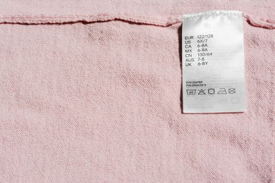 Clothing label on pink garment, top view