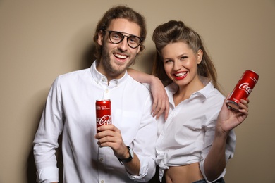 Photo of MYKOLAIV, UKRAINE - NOVEMBER 28, 2018: Young couple with Coca-Cola cans on color background