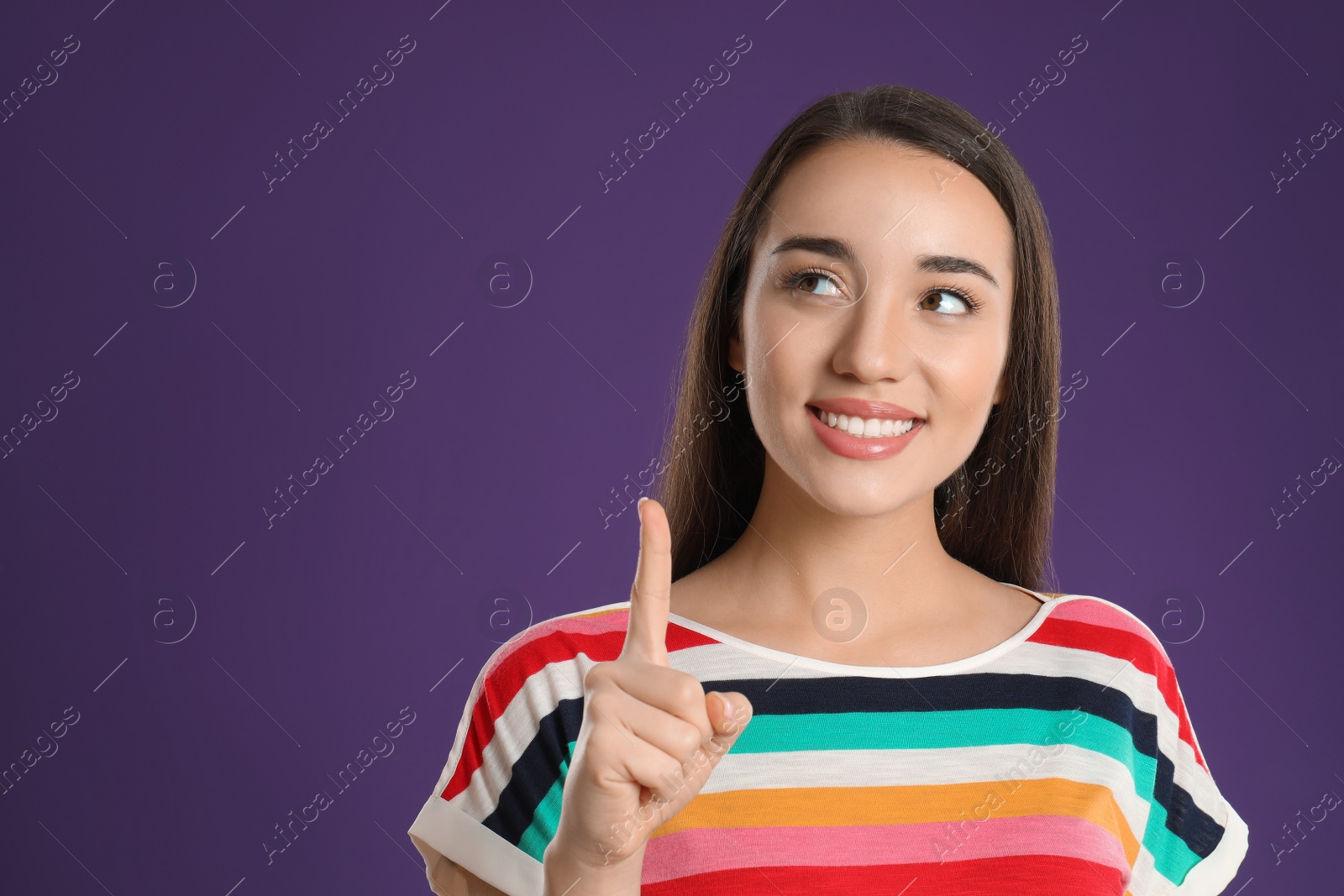 Photo of Woman showing number one with her hand on purple background. Space for text