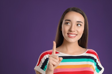 Photo of Woman showing number one with her hand on purple background. Space for text