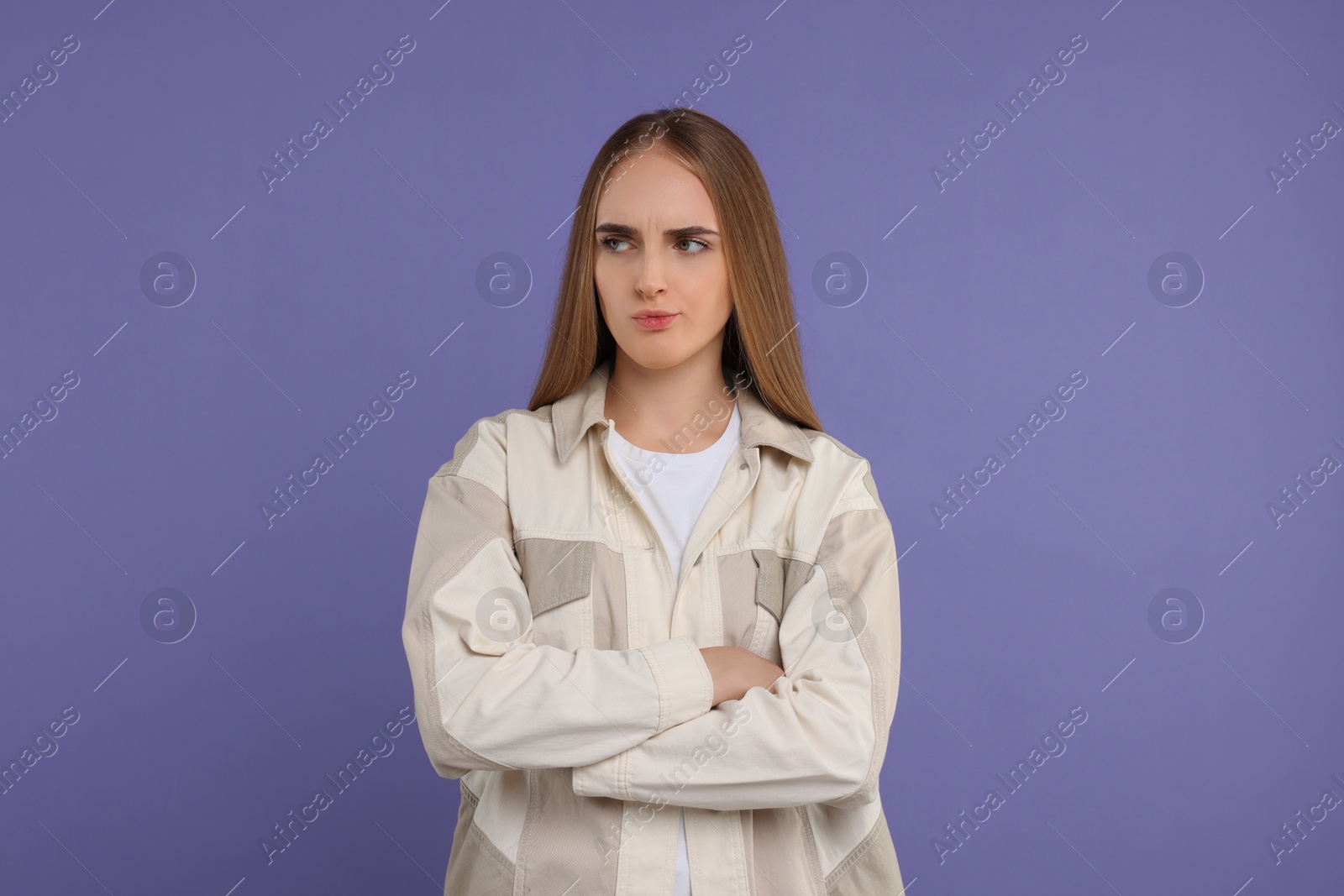 Photo of Resentful woman with crossed arms on violet background