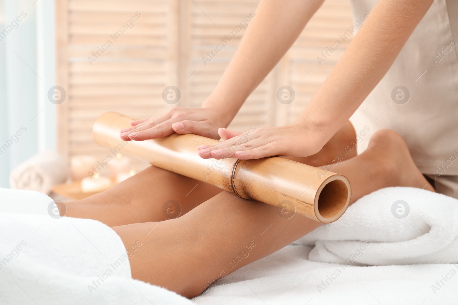 Photo of Woman having massage with bamboo stick in wellness center, closeup