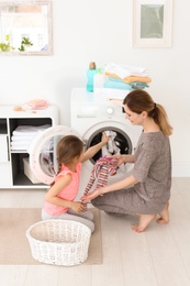 Photo of Housewife with little daughter doing laundry at home