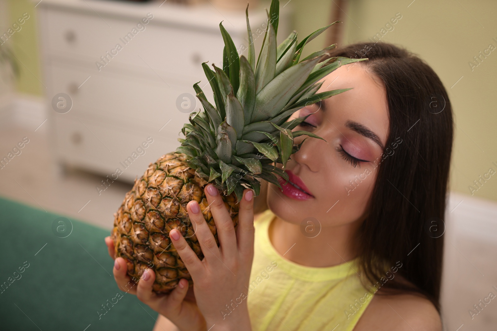 Photo of Young woman with fresh pineapple at home. Exotic fruit