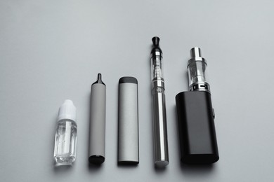 Different electronic cigarettes and liquid solution on light background