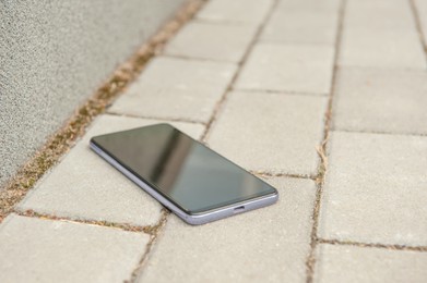 Photo of Smartphone on pavement outdoors, space for text. Lost and found