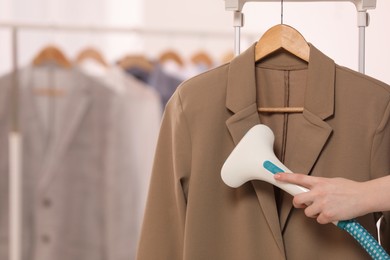 Photo of Woman steaming jacket on hanger in room, closeup. Space for text