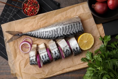 Tasty salted mackerel, onion and lemon on wooden table, flat lay