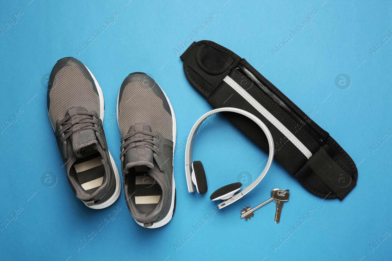 Photo of Flat lay composition with stylish black waist bag on light blue background