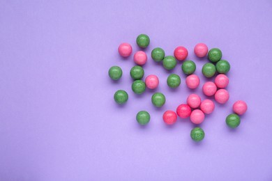 Photo of Many bright chewy gumballs on lilac background, flat lay. Space for text