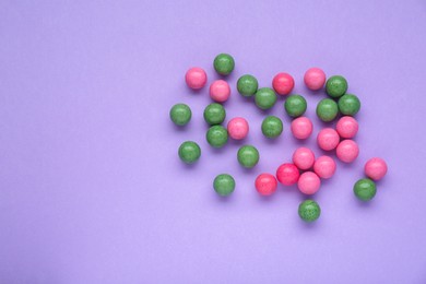 Many bright chewy gumballs on lilac background, flat lay. Space for text