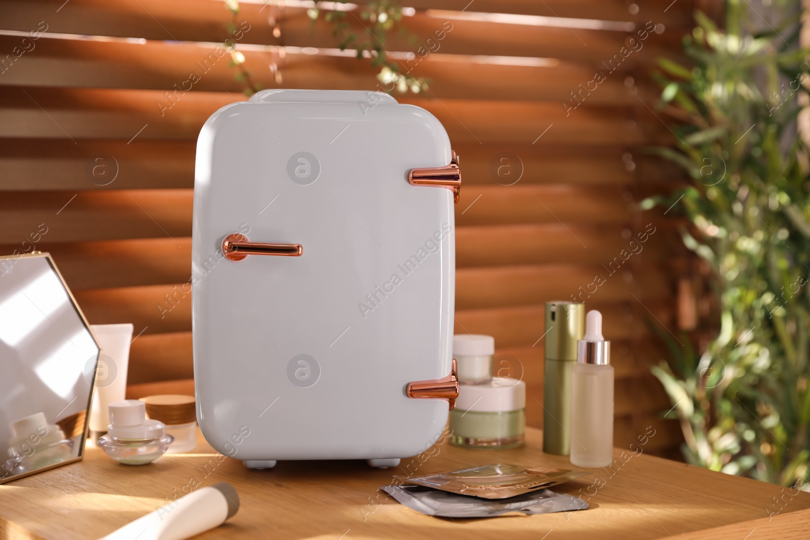 Photo of Mini fridge for cosmetic products on wooden vanity table