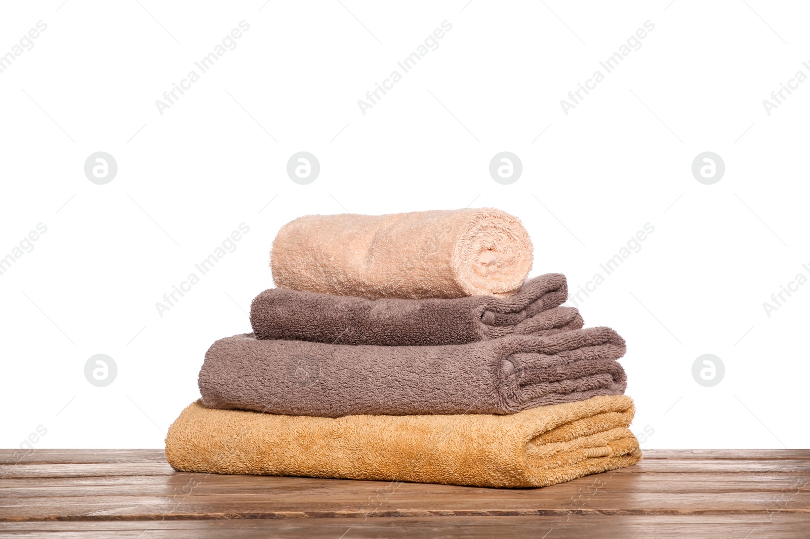 Photo of Soft colorful terry towels on wooden table against white background