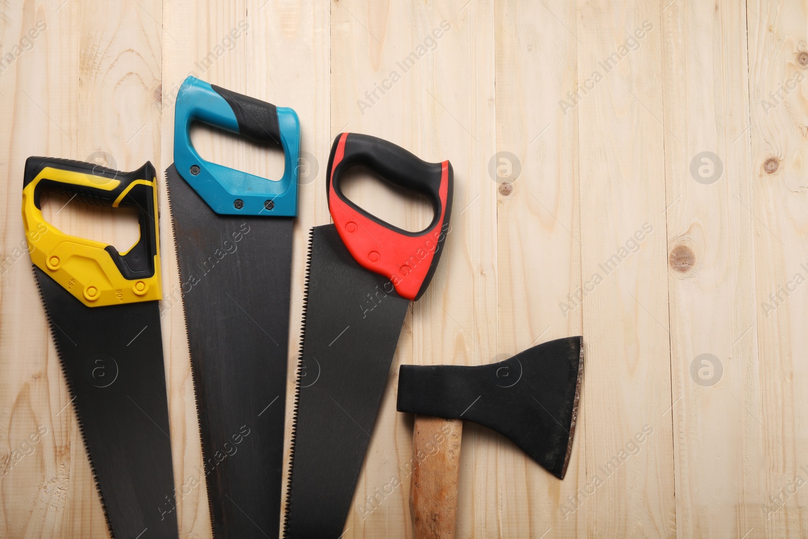 Photo of Saws with colorful handles on wooden background, flat lay. Space for text