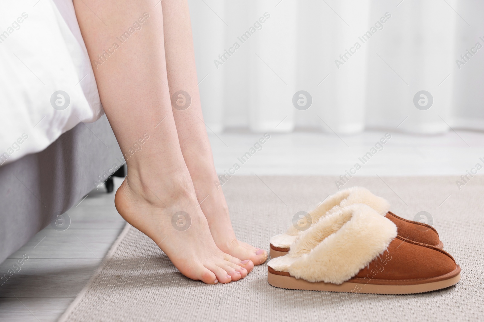 Photo of Woman near brown soft slippers at home, closeup
