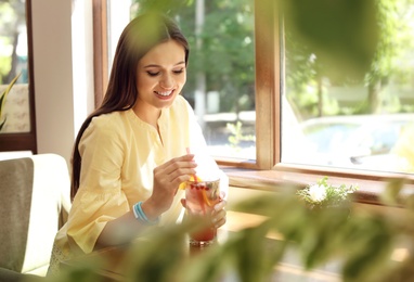 Young woman with glass of tasty natural lemonade in cafe. Detox drink