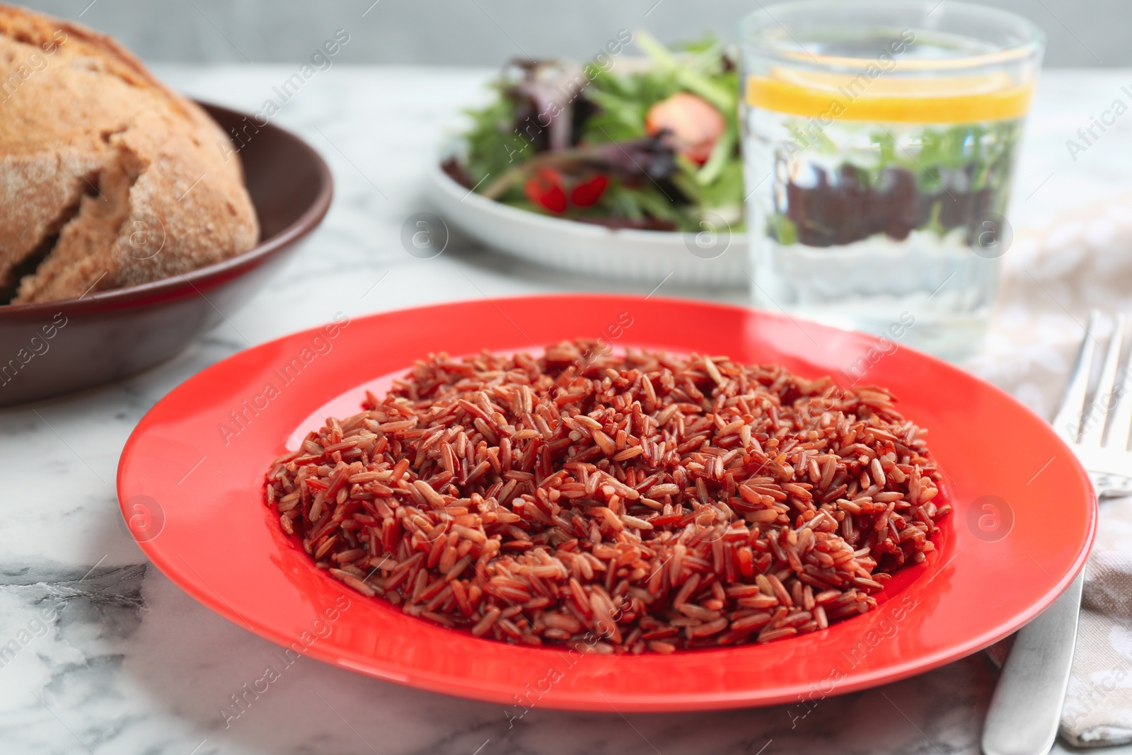 Photo of Tasty brown rice served on white marble table