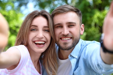 Photo of Happy young couple taking selfie in park