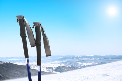 Image of Trekking poles and beautiful view of snowy mountains on sunny day. Space for text