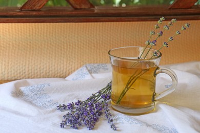 Photo of Tasty herbal tea and fresh lavender flowers on white fabric, space for text
