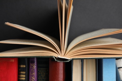 Photo of Different hardcover books against black background, closeup