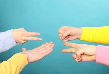 People playing rock, paper and scissors on light blue background, closeup