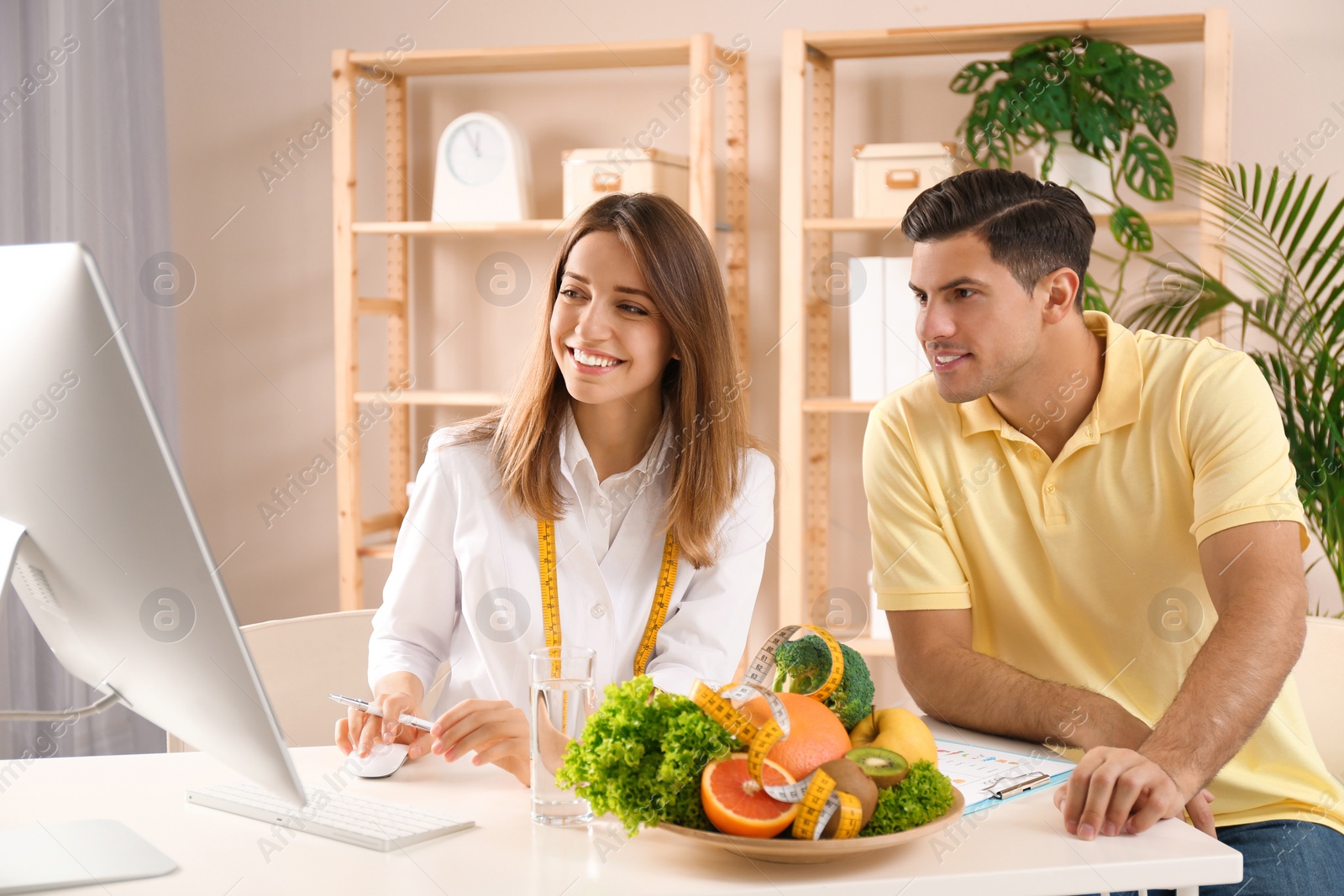 Photo of Young nutritionist consulting patient at table in clinic