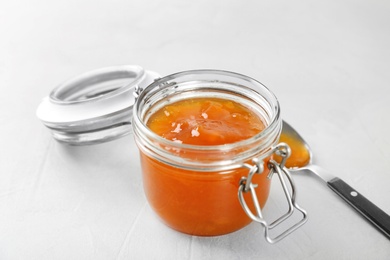 Photo of Jar and spoon with sweet jam on light background