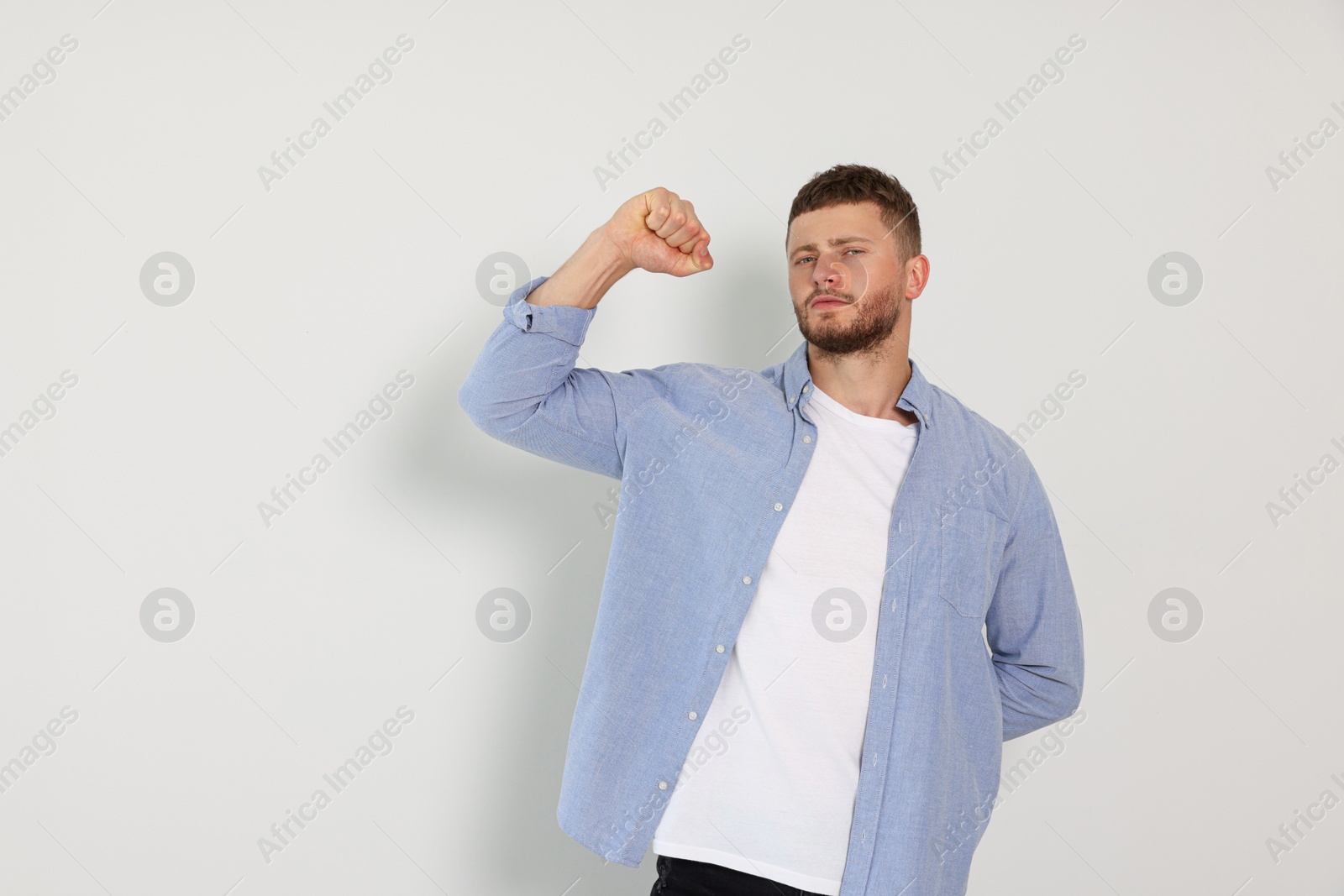 Photo of Young man showing arm on white background. Space for text