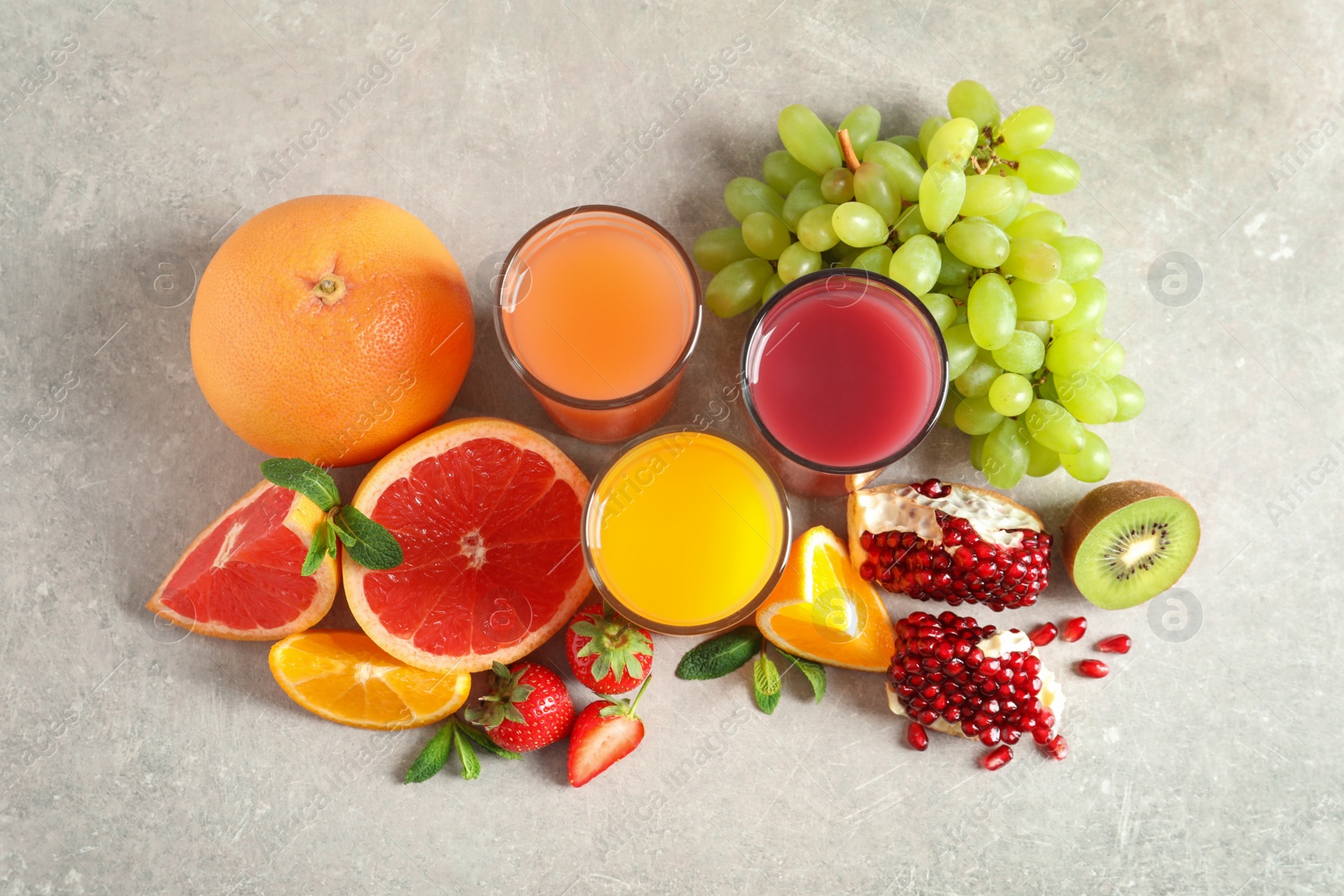 Photo of Glasses of different juices and fresh fruits on table, top view