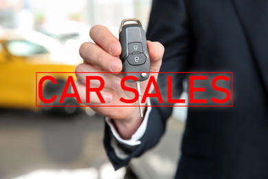 Image of Salesman with key in car dealership, closeup