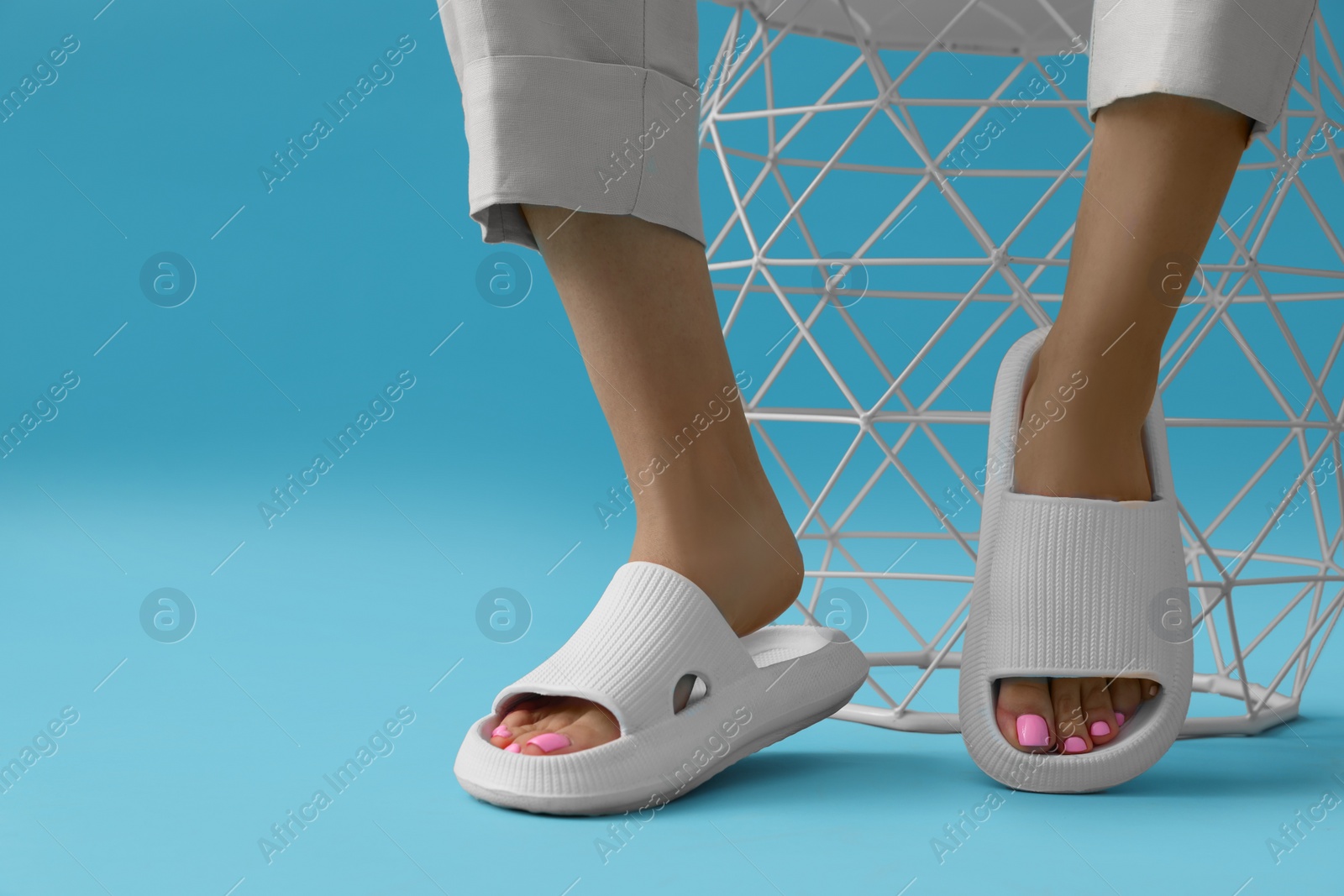 Photo of Woman wearing comfortable rubber slippers on light blue background, closeup. Space for text