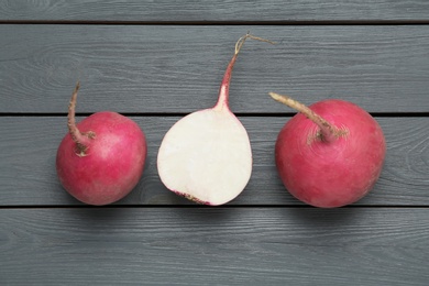 Photo of Raw red turnips on grey wooden table, flat lay