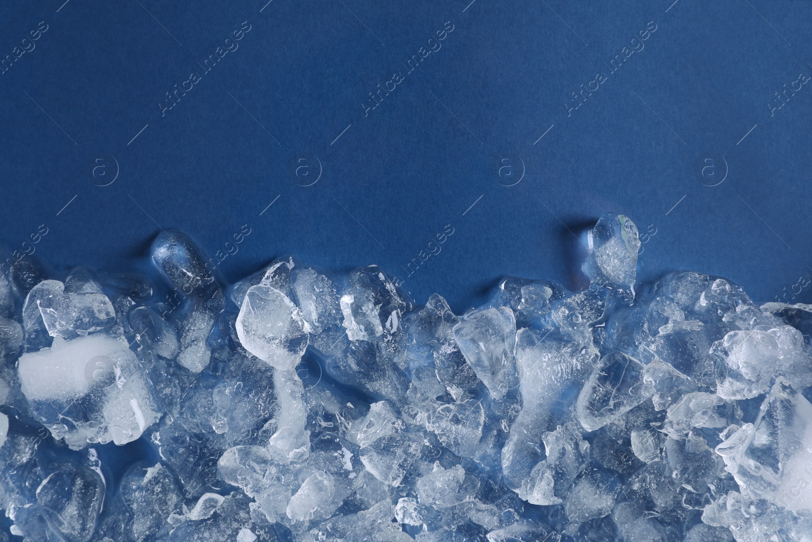 Photo of Pile of crushed ice on blue background, top view. Space for text