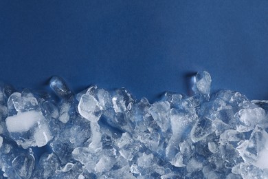 Pile of crushed ice on blue background, top view. Space for text