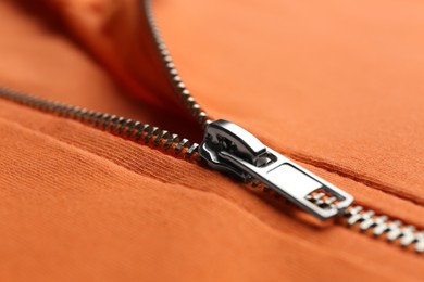 Photo of Orange sweatshirt with zipper as background, closeup view